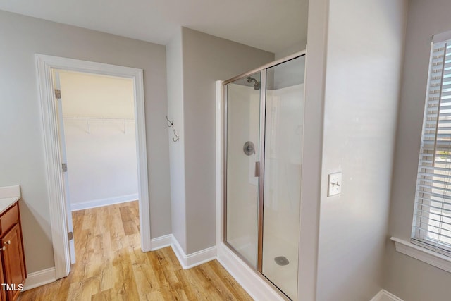 full bath with a spacious closet, baseboards, a stall shower, wood finished floors, and vanity