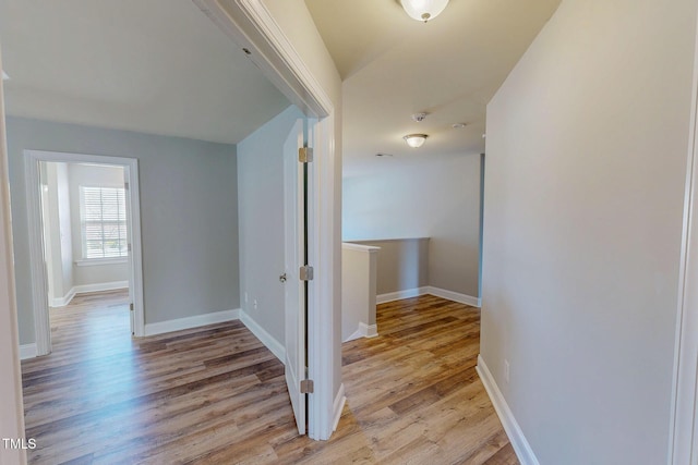 corridor with light wood-style floors and baseboards