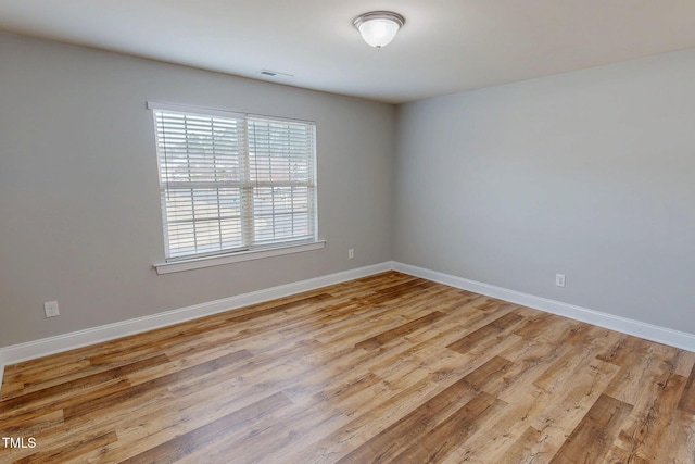 unfurnished room featuring visible vents, baseboards, and wood finished floors