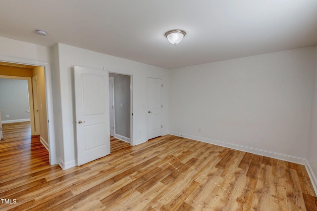 unfurnished bedroom with attic access, baseboards, and light wood-style floors