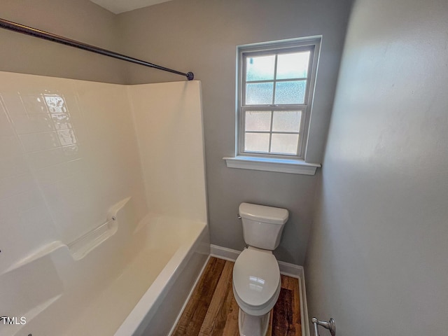 full bath featuring shower / bathing tub combination, toilet, wood finished floors, and baseboards