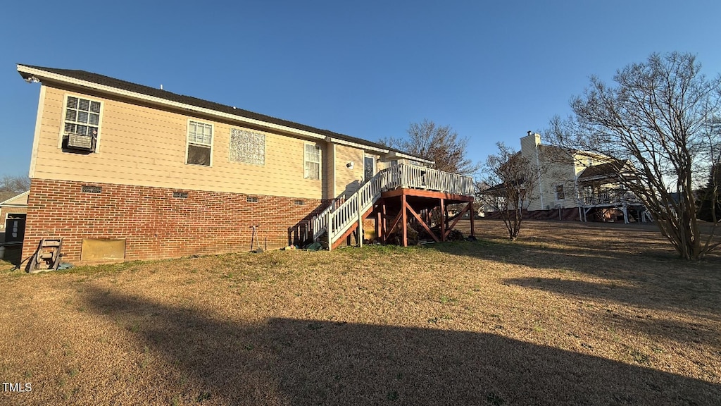 back of house featuring brick siding, stairway, a lawn, and a deck