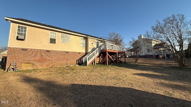 back of house featuring brick siding, stairway, a lawn, and a deck