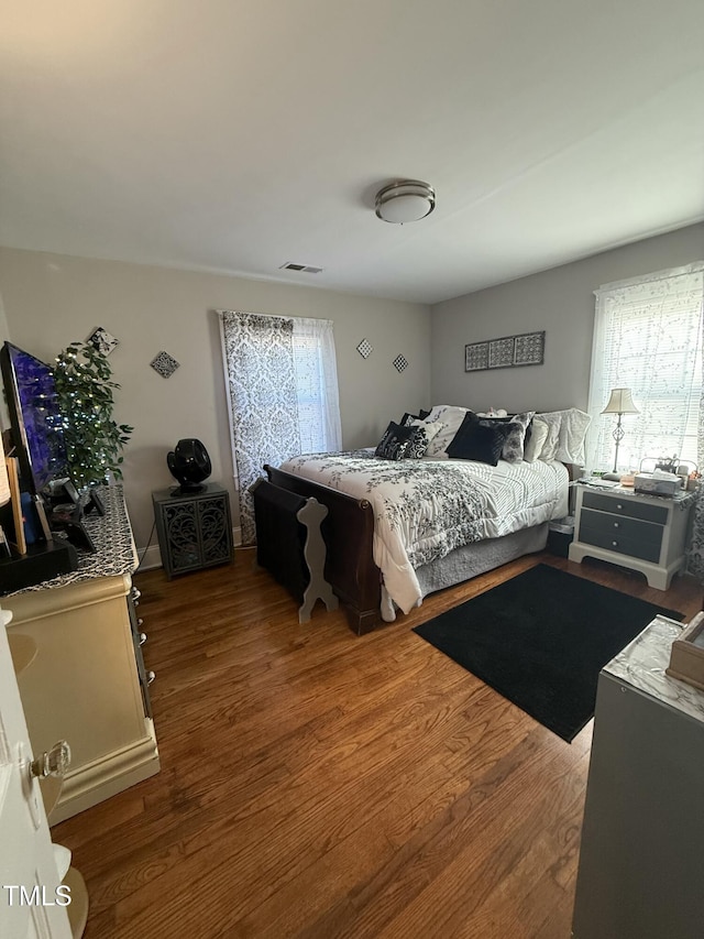 bedroom with visible vents, multiple windows, and wood finished floors