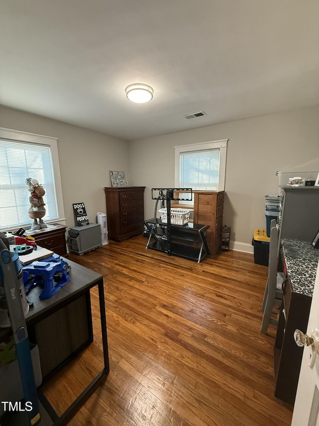 office area with visible vents, baseboards, a healthy amount of sunlight, and wood finished floors