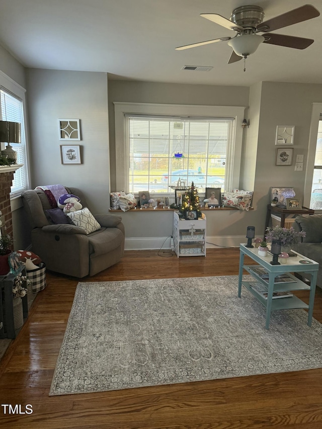 living area with visible vents, baseboards, ceiling fan, and wood finished floors