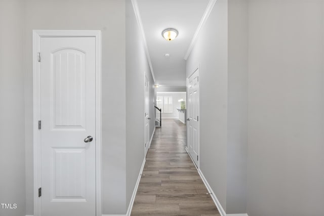 hall with wood finished floors, baseboards, and ornamental molding