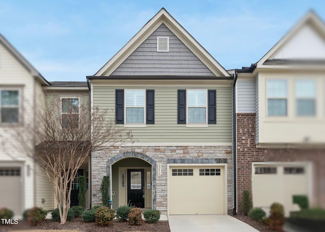 townhome / multi-family property with stone siding, an attached garage, and concrete driveway