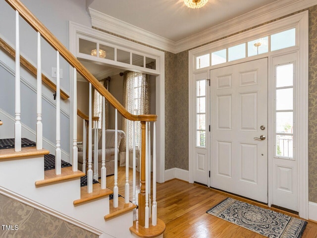 foyer entrance featuring a wealth of natural light, stairway, crown molding, and wood finished floors