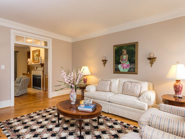 living area with baseboards, wood finished floors, a glass covered fireplace, and crown molding