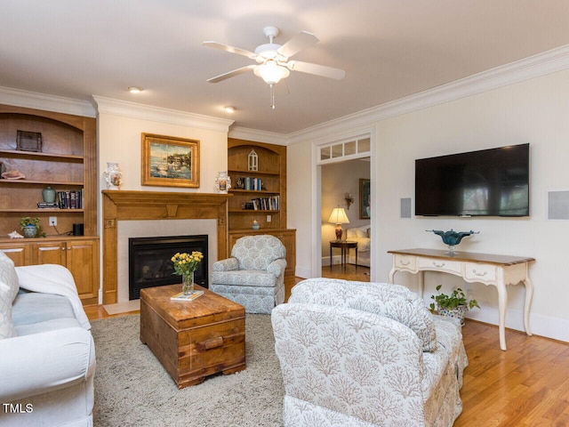 living area featuring a fireplace with flush hearth, baseboards, light wood-type flooring, and ornamental molding