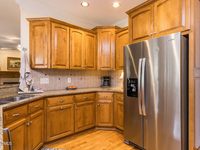 kitchen with light stone counters, stainless steel fridge with ice dispenser, tasteful backsplash, and ornamental molding