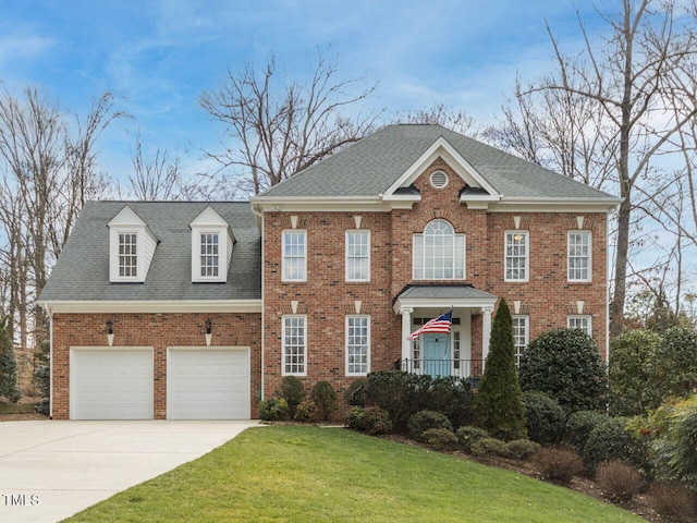 colonial house with a front lawn, concrete driveway, brick siding, and an attached garage