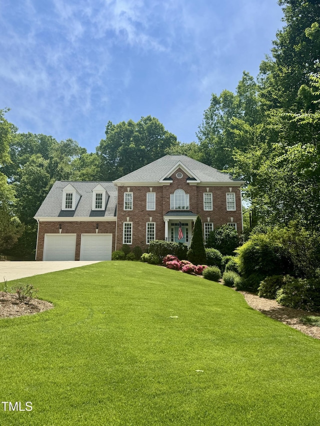colonial home featuring concrete driveway, brick siding, and a front yard