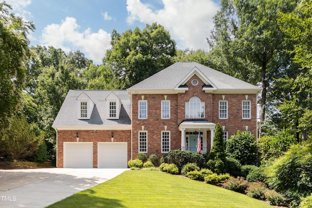 3359 Hampton Rd, Raleigh, NC 27607 - colonial inspired home with concrete driveway, a front yard, brick siding, a garage, and view of scattered trees