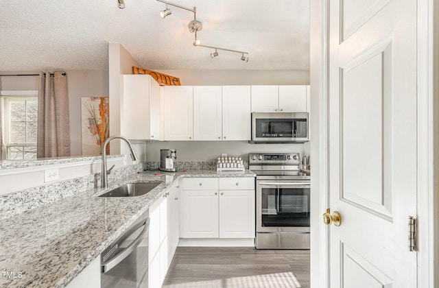 kitchen featuring a sink, a textured ceiling, white cabinetry, and stainless steel appliances