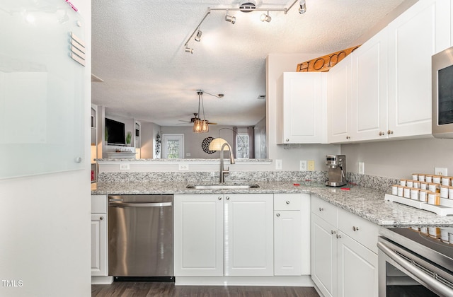 kitchen featuring a textured ceiling, white cabinets, appliances with stainless steel finishes, and a sink