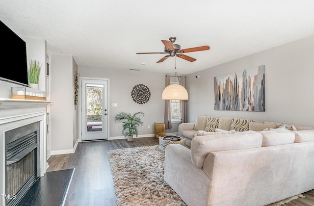 living area featuring a ceiling fan, wood finished floors, a fireplace, and baseboards