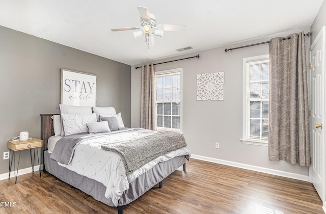 bedroom featuring visible vents, a ceiling fan, baseboards, and wood finished floors