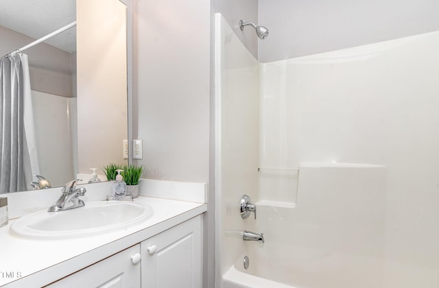 bathroom featuring a textured ceiling, shower / bath combo with shower curtain, and vanity