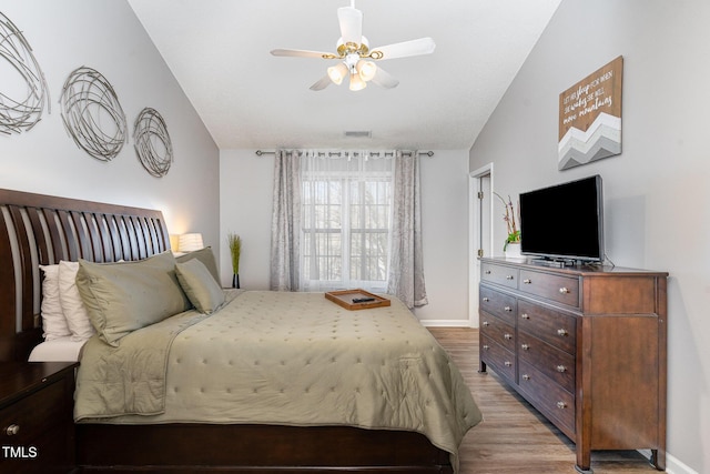 bedroom featuring baseboards, light wood-type flooring, lofted ceiling, and visible vents