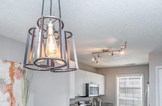 interior details with white cabinetry, a textured ceiling, and stainless steel appliances