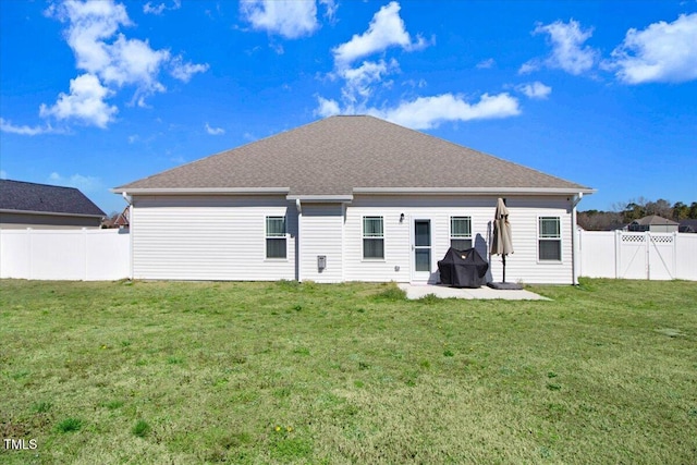 rear view of house with a lawn, a fenced backyard, and a shingled roof