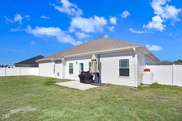 rear view of property with a yard, roof with shingles, a fenced backyard, and a patio area