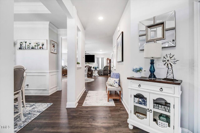 hall with a wainscoted wall, ornamental molding, recessed lighting, a decorative wall, and dark wood-style flooring