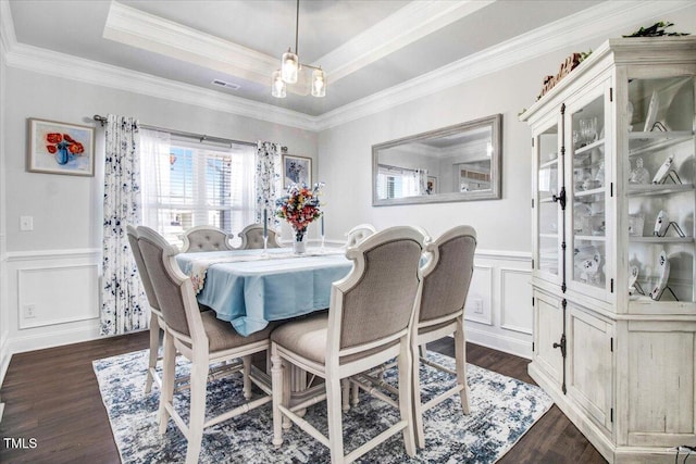 dining room with dark wood finished floors, a decorative wall, a raised ceiling, and visible vents