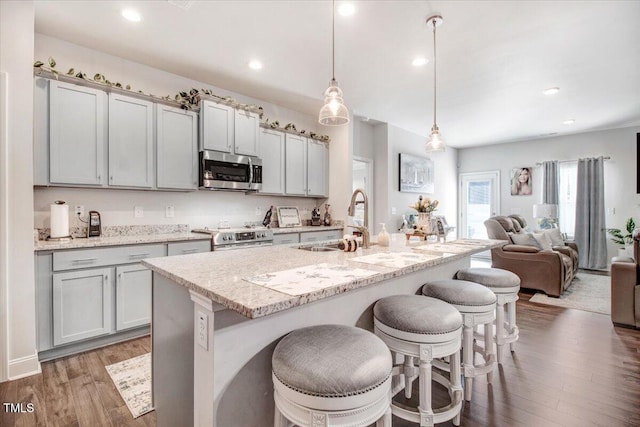 kitchen with open floor plan, a kitchen bar, light wood-style floors, stainless steel appliances, and a sink