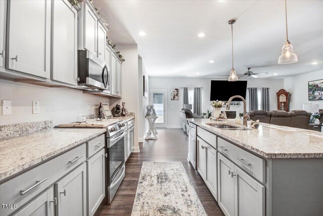 kitchen with a sink, appliances with stainless steel finishes, open floor plan, and gray cabinetry