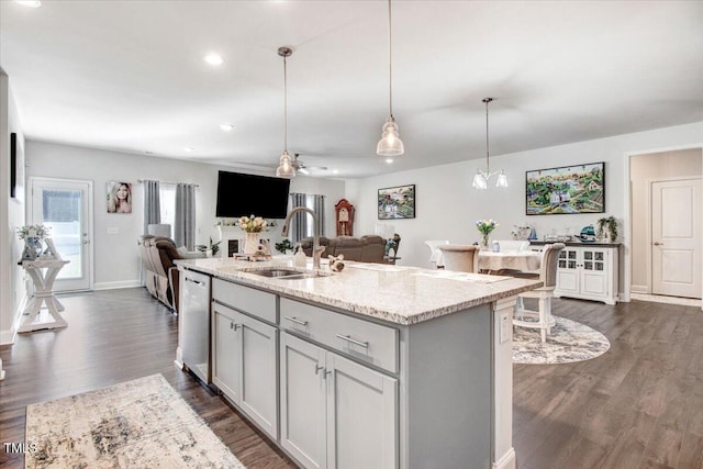 kitchen with a sink, light stone countertops, dishwasher, gray cabinets, and dark wood-style flooring