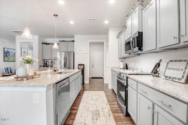 kitchen featuring light wood finished floors, visible vents, a sink, appliances with stainless steel finishes, and a kitchen island with sink