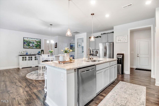 kitchen featuring visible vents, a sink, light stone counters, stainless steel appliances, and dark wood-style flooring