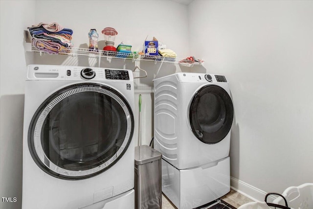 laundry area featuring laundry area, washing machine and dryer, and baseboards