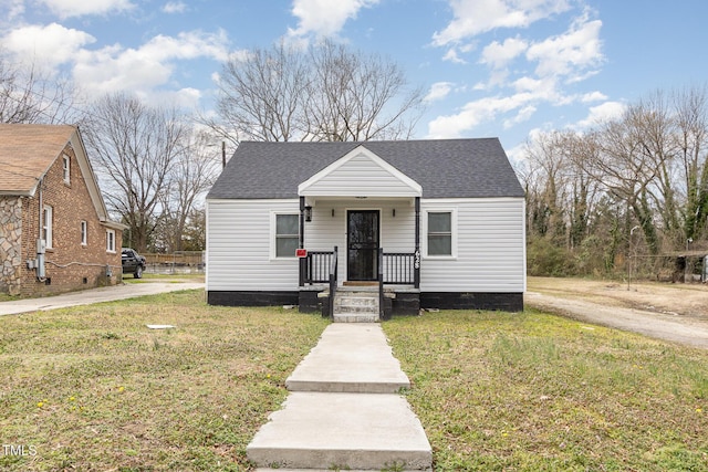 bungalow-style home with roof with shingles and a front yard