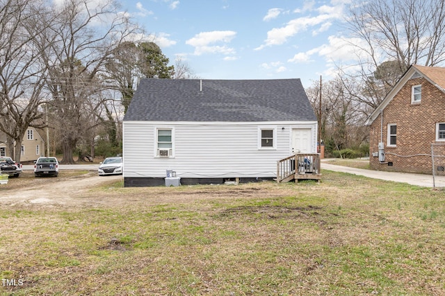 view of side of home with a yard and roof with shingles