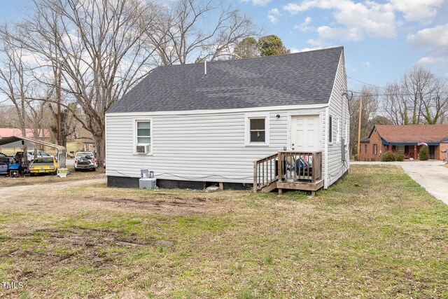 rear view of property featuring a yard, cooling unit, driveway, and roof with shingles