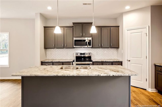 kitchen with visible vents, stainless steel appliances, light wood-style floors, and decorative backsplash