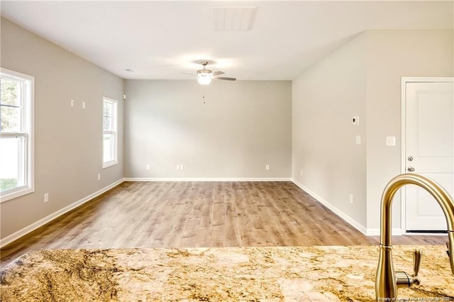 empty room with visible vents, a healthy amount of sunlight, light wood-style flooring, and a ceiling fan