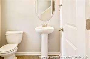 bathroom featuring toilet, baseboards, and wood finished floors