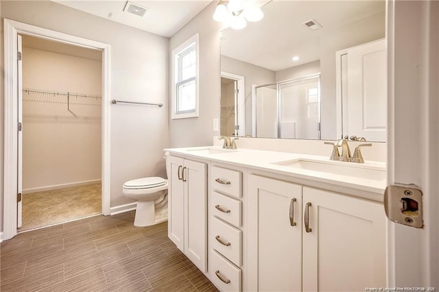 bathroom with visible vents, a stall shower, toilet, and a sink