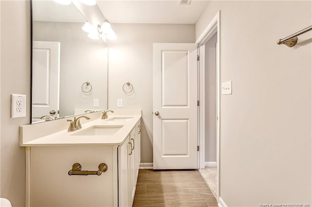 full bath featuring a sink, visible vents, baseboards, and double vanity