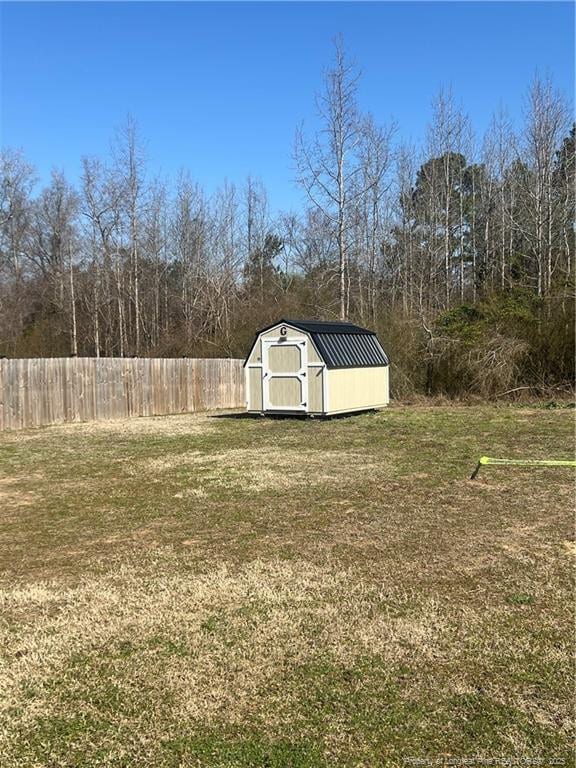 view of yard with an outbuilding, a storage shed, and fence