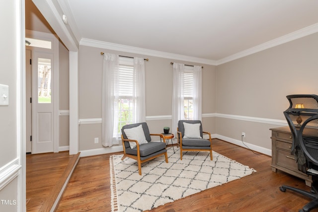 living area featuring crown molding, wood finished floors, baseboards, and a healthy amount of sunlight