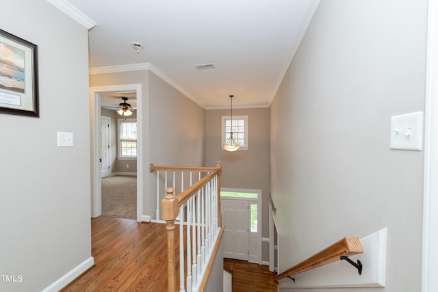 staircase featuring visible vents, crown molding, baseboards, and wood finished floors