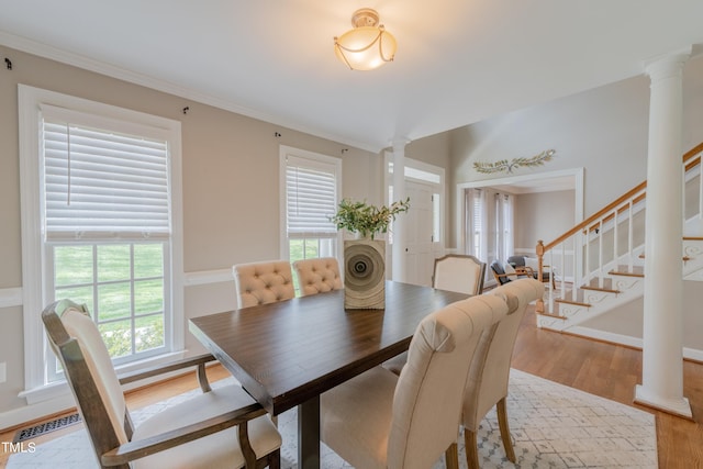 dining space featuring visible vents, light wood finished floors, stairway, and ornate columns