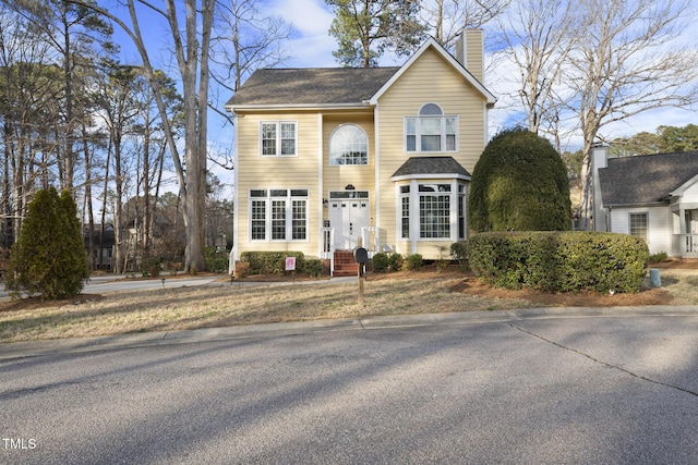 view of front of house with roof with shingles and a chimney