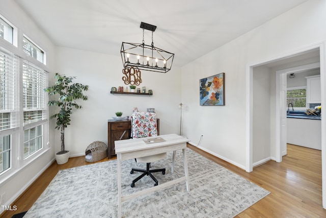 office space with light wood-style flooring, baseboards, and a chandelier